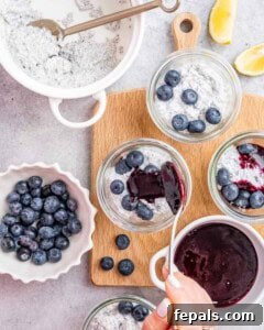 Ingredients spread out on a wooden board with bowls of blueberries and lemon chia pudding ready for layering into jars.