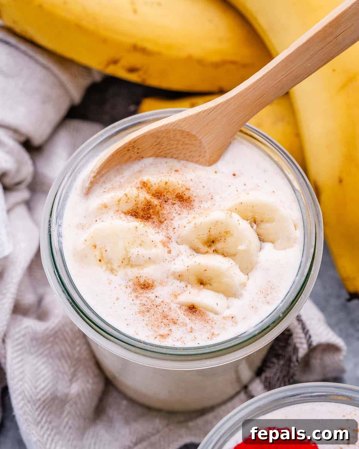 Smooth Overnight Oats 11 Close up image of creamy blended rolled oats in a jar, beautifully topped with fresh banana slices.