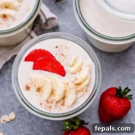 Blended oats in a jar topped with sliced bananas and strawberries, a perfect quick breakfast.