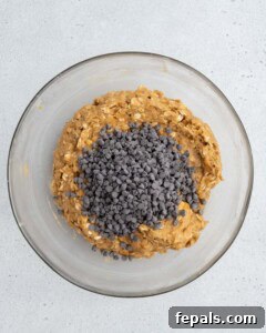 Chocolate chips are added to a bowl with the cookie dough mixture.