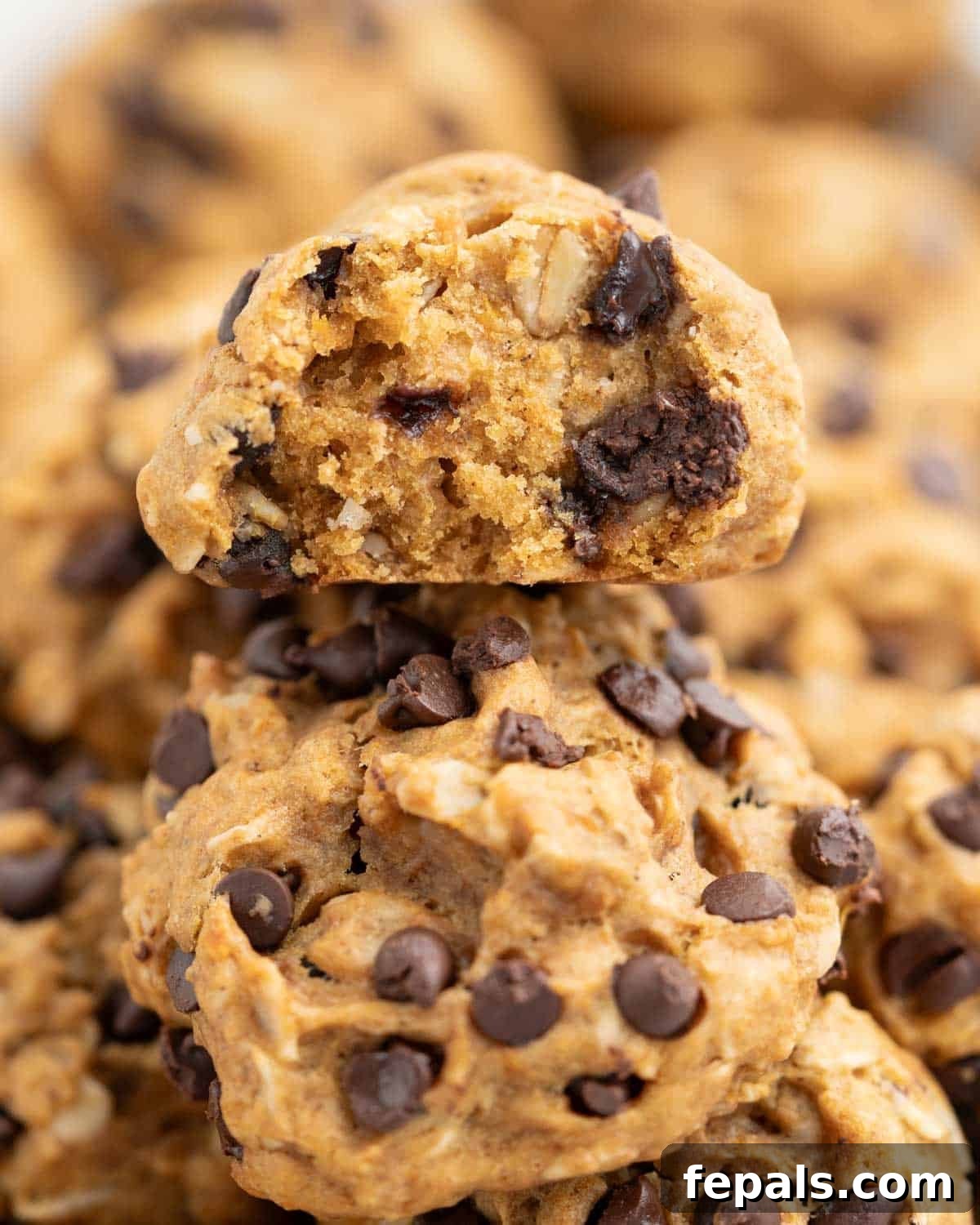A stack of soft, fluffy sweet potato cookies, with one cookie showing a bite taken out, revealing its moist interior and chocolate chips.
