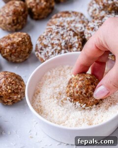 Cookie dough being rolled in shredded coconut and shaped into patties.