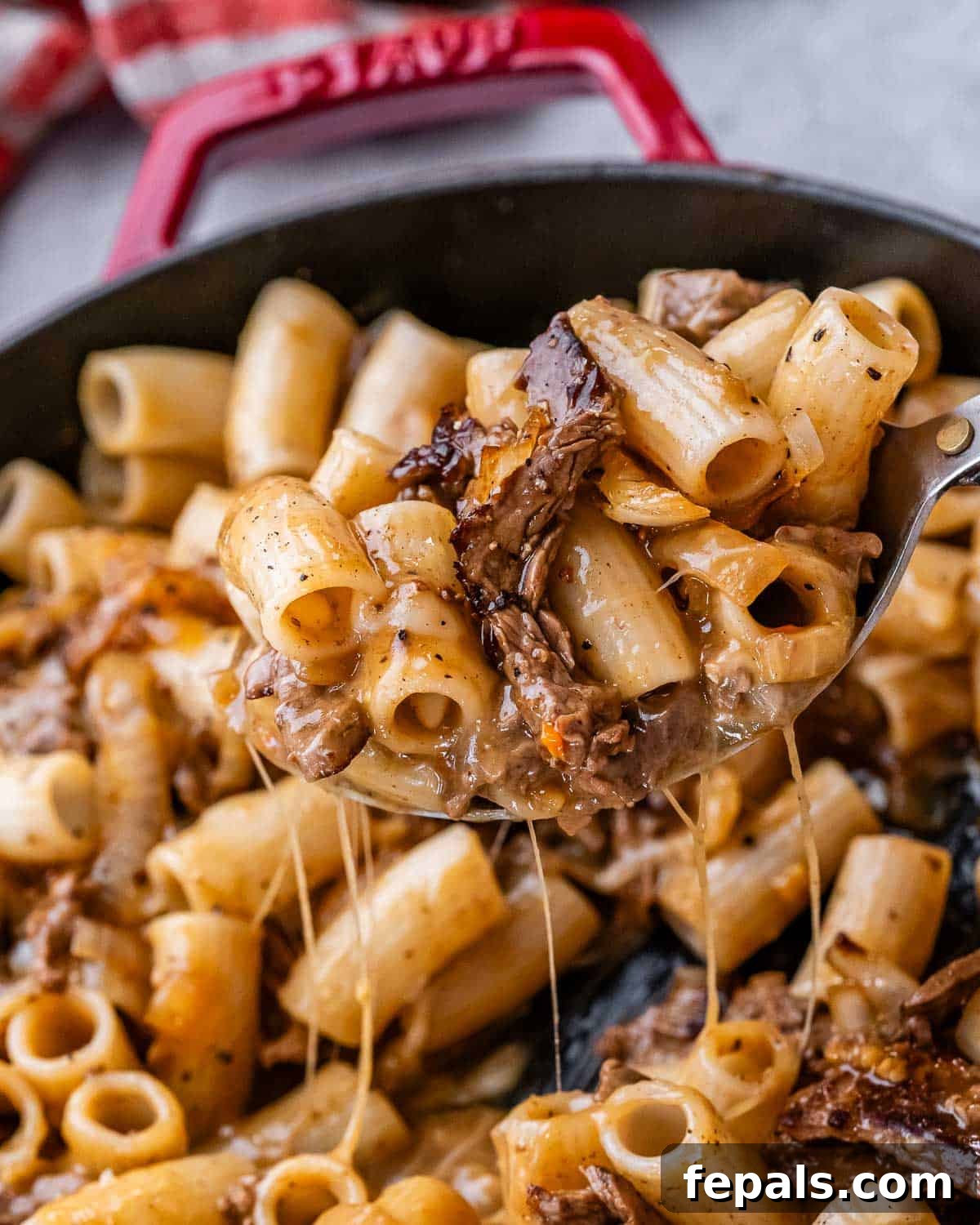 Loaded Philly Cheesesteak Pasta 2 A spoonful of Philly cheesesteak pasta with melted provolone