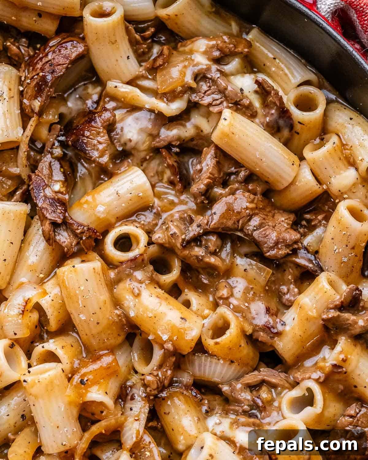 Loaded Philly Cheesesteak Pasta 8 A closeup of Philly cheesesteak pasta in a cast iron skillet