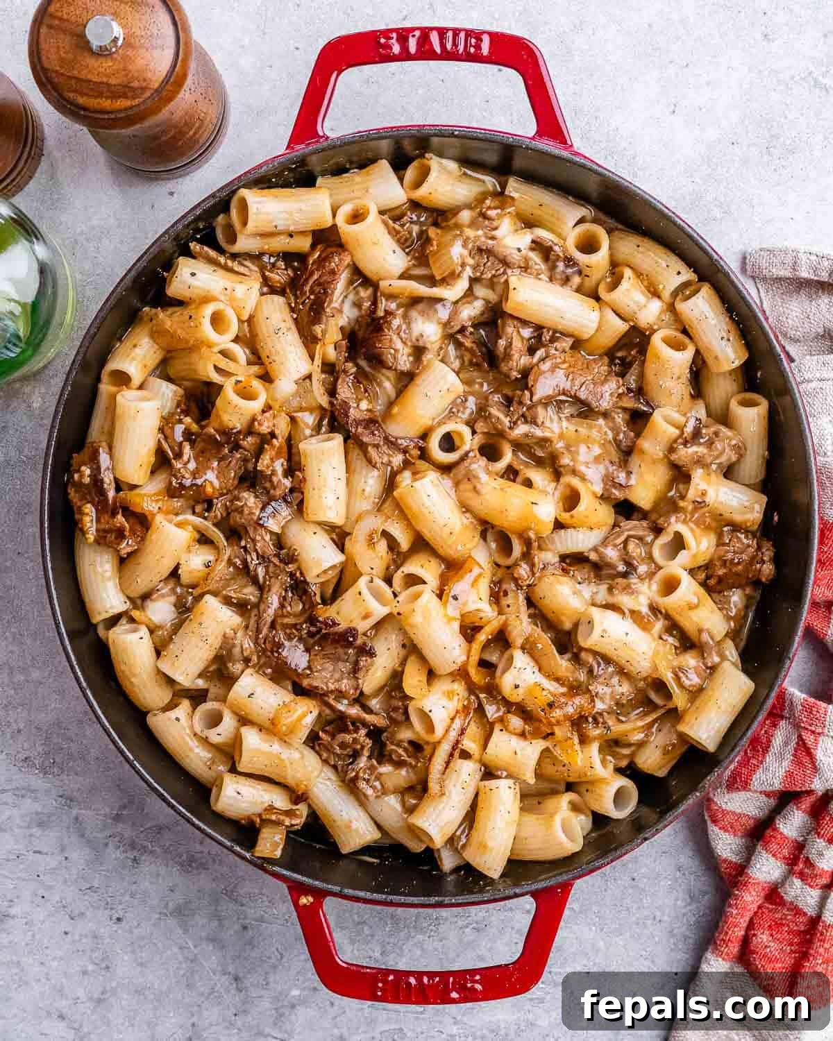 Loaded Philly Cheesesteak Pasta 7 A red skillet with cheesy pasta and steak bites.