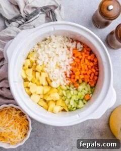 The full crockpot filled with potatoes, chopped carrots, celery, onion.