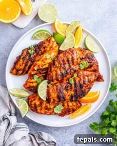 Plate of grilled pollo asada chicken served with lime wedges and cilantro for garnish.