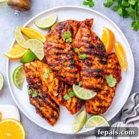 grilled chicken with asada sauce on a plate with lime and lemon wedges.