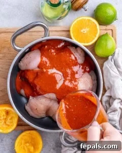 Fresh citrus marinade being poured over raw chicken breasts in a mixing bowl.