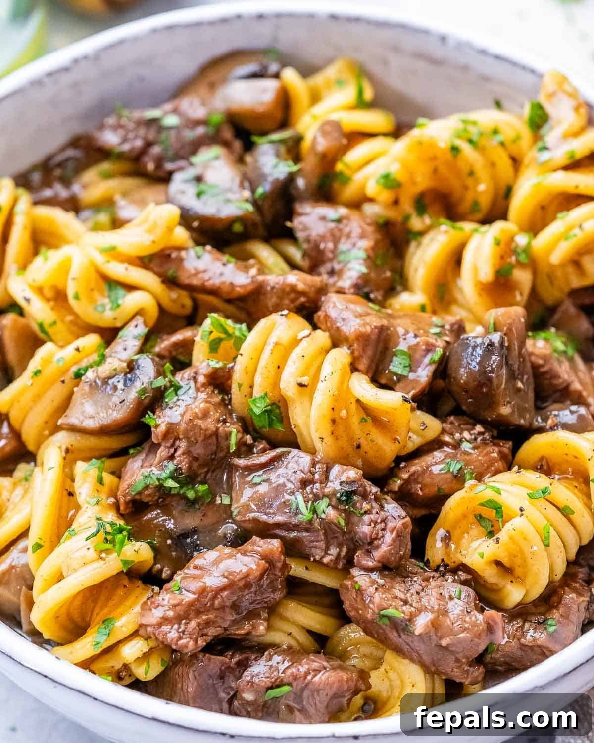 Quick and Creamy Instant Pot Beef Stroganoff 2 Close-up of cooked beef stroganoff with tender beef, mushrooms, and pasta coated in a creamy sauce.