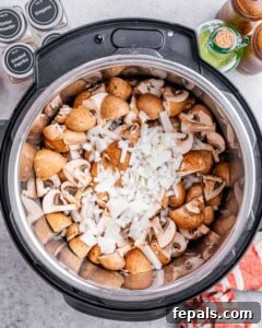 Top view of the instant pot with onion and mushrooms in it.