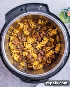 Overhead shot of beef stroganoff served inside the Instant Pot with golden pasta and mushrooms.