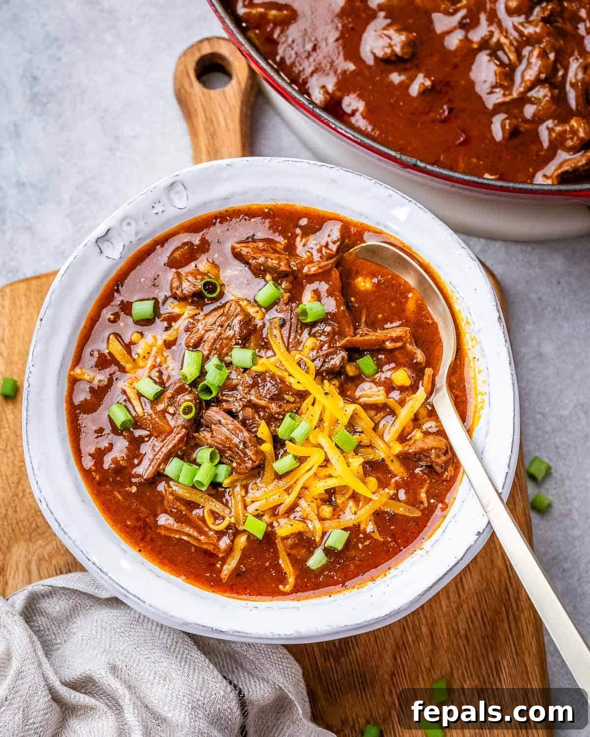 Texas chili in a white bowl on a wooden board