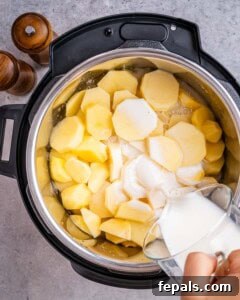 Milk being poured into an Instant Pot with sliced potatoes.