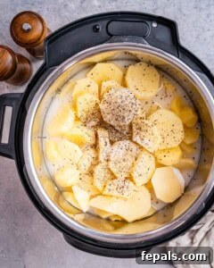 Pressure cooker pot with sliced potatoes seasoned generously with salt and black pepper.