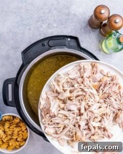 Shredded chicken on a plate being returned to the Instant Pot filled with soup broth.