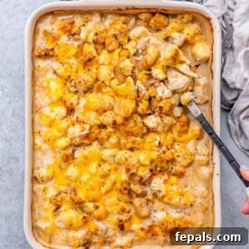 A dish with chicken and cauliflower topped with golden melted cheese, ready to serve.