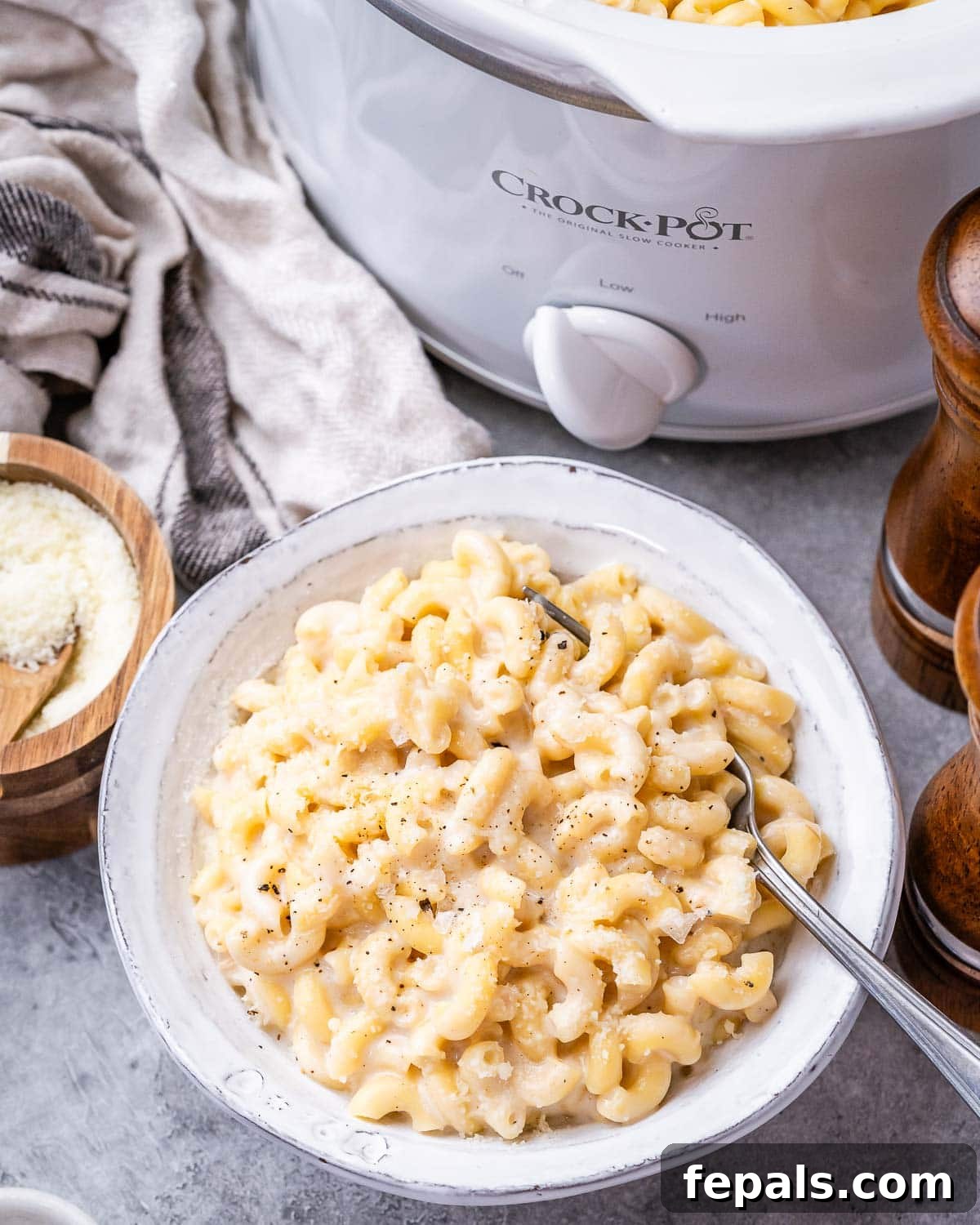 Slow Cooker Cheesy Dream 12 A large white bowl of creamy mac and cheese next to a gleaming crockpot, ready for serving.