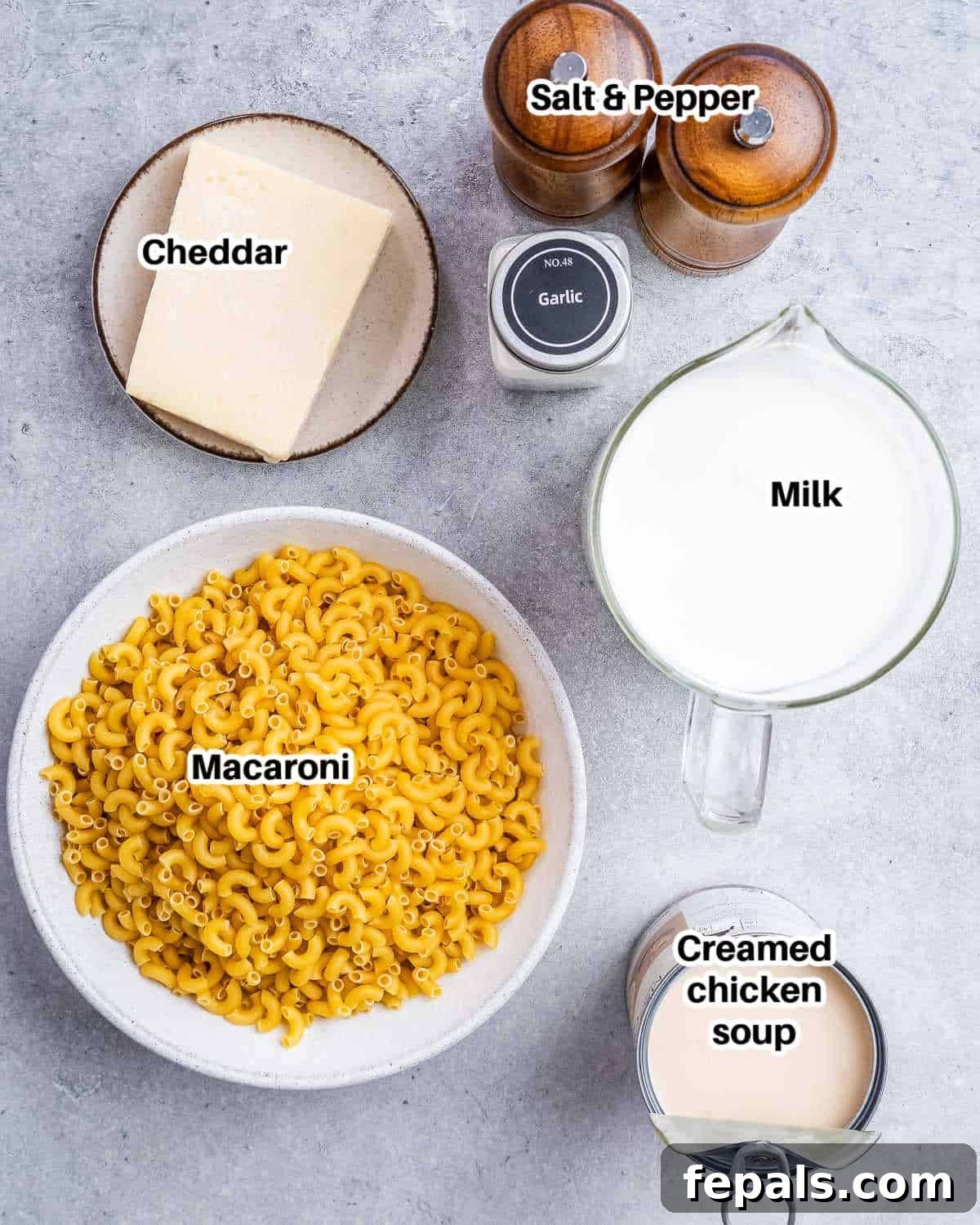 Slow Cooker Cheesy Dream 3 A selection of fresh ingredients including elbow pasta, milk, cheese block, and cream of chicken soup, laid out for making crockpot mac and cheese.