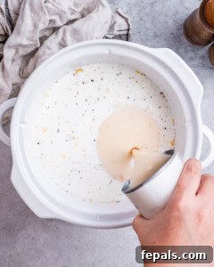 Mixing creamed chicken soup and shredded cheddar cheese into the pasta mixture in the crockpot.