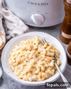 A bowl of finished crockpot mac and cheese, garnished with pepper, ready to serve.