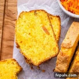 Two slices of carrot cake loaf on parchment paper, with soft crumbs and visible raisins.