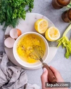 Avgolemono Soup: A Bowl of Bright Comfort 12 A bowl of whisked egg and lemon mixture with lemon halves, celery, and herbs nearby on the counter.