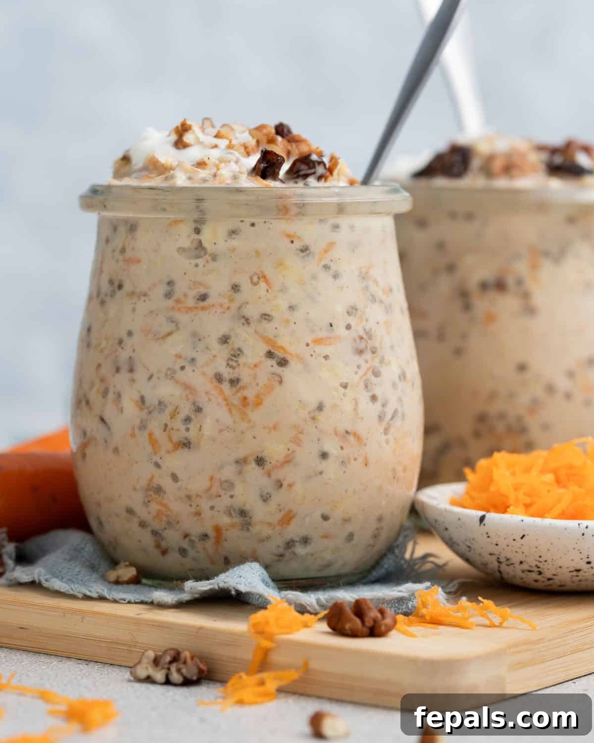 Spiced Carrot Cake Overnight Oats 13 Two jars of ready-to-eat carrot cake overnight oats displayed on a rustic wooden board.