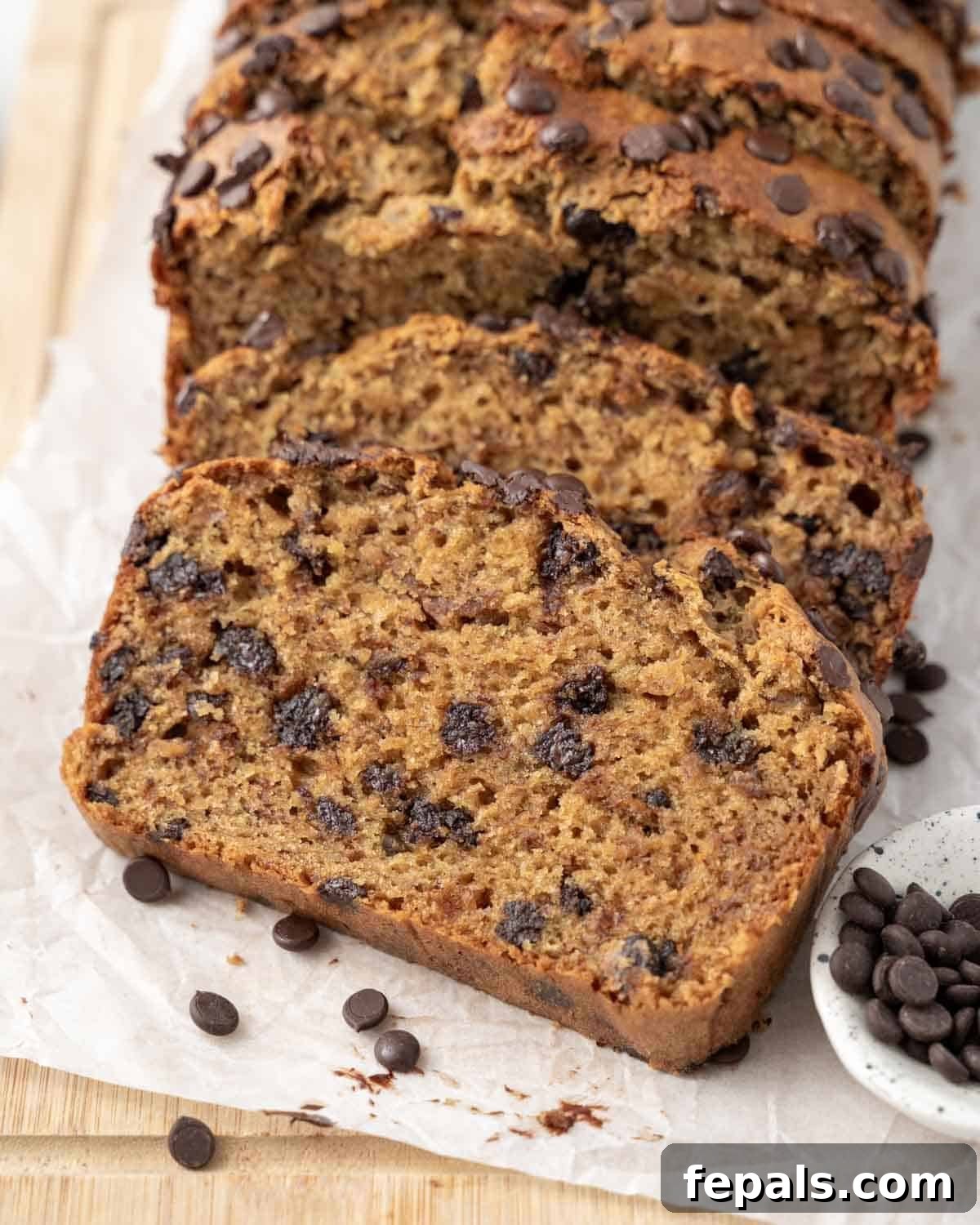 A freshly baked slice of Peanut Butter Chocolate Chip Banana Bread on a cutting board, revealing its moist texture and abundant chocolate chips.