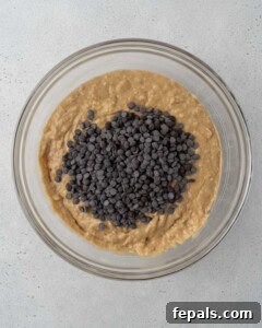 chocolate chips added over banana bread dough in a bowl.