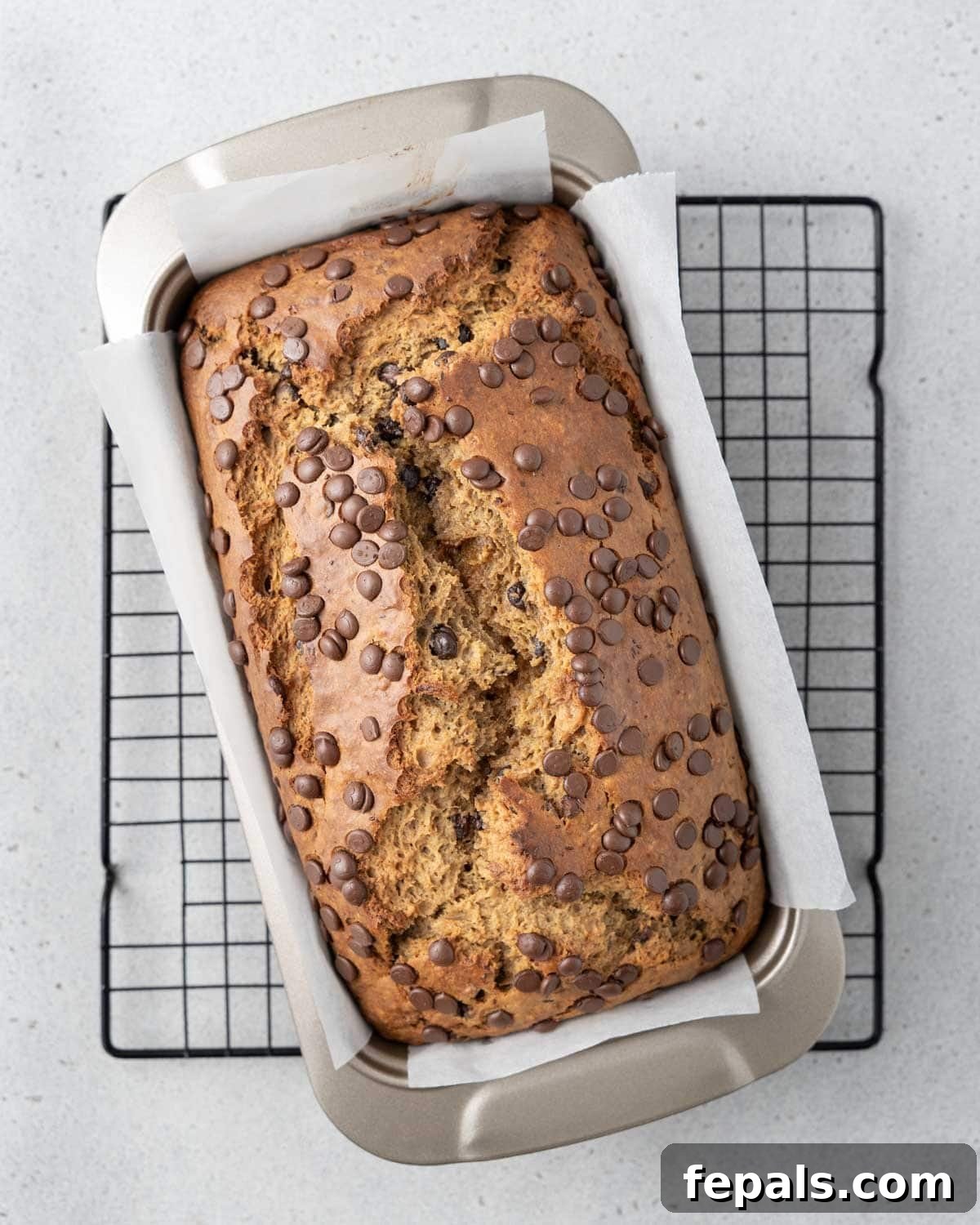 Freshly baked banana bread cooling on a wire rack in a loaf pan, ready to be sliced and enjoyed.