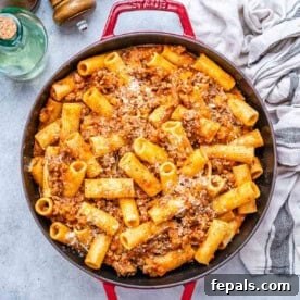 a red skillet with pasta and red beef sauce.