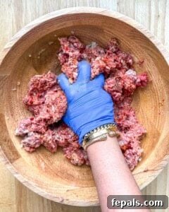 A ball of meat mixture placed between two sheets of parchment paper.