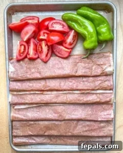 Cooked doner kebab being unraveled from parchment paper on a baking sheet.