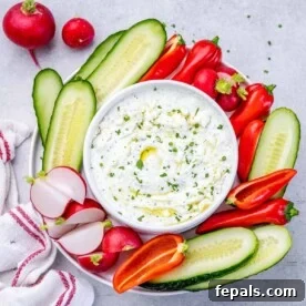Top view of a creamy feta dip in a stylish bowl, surrounded by a colorful assortment of fresh veggies, making it an appealing and healthy appetizer.