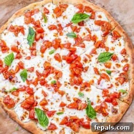 Overhead shot of a full bruschetta pizza, beautifully seasoned and adorned with fresh basil leaves scattered across its top, inviting a delicious bite.
