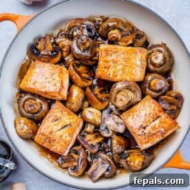 Top view of pan-seared salmon with mushrooms on an orange skillet
