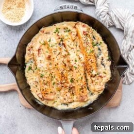 4 cooked salmon fillets in a skillet over a creamy sauce.