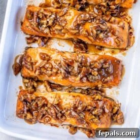 Baked salmon topped with pecans glazed with maple syrup in a white baking dish.