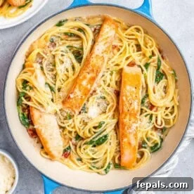 A blue skillet with spaghetti and 3 salmon fillets.