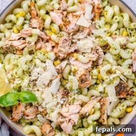 Pasta in a bowl topped with salmon flaked into small bite sizes.
