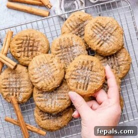Cookies on a cooling rack with one hand reaching for a cookie.