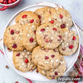 Top view of cranberry oatmeal cookies spread over each other on a white round plate.