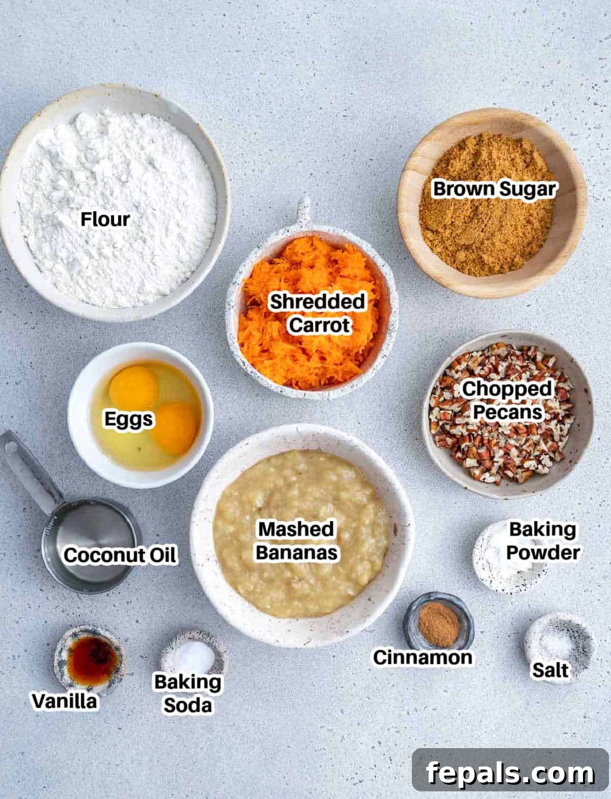 A collection of fresh ingredients laid out for making carrot banana muffins, including carrots, bananas, flour, and spices.
