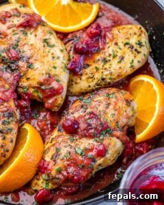 Chicken breasts cooked in a pan with cranberry sauce and oranges.