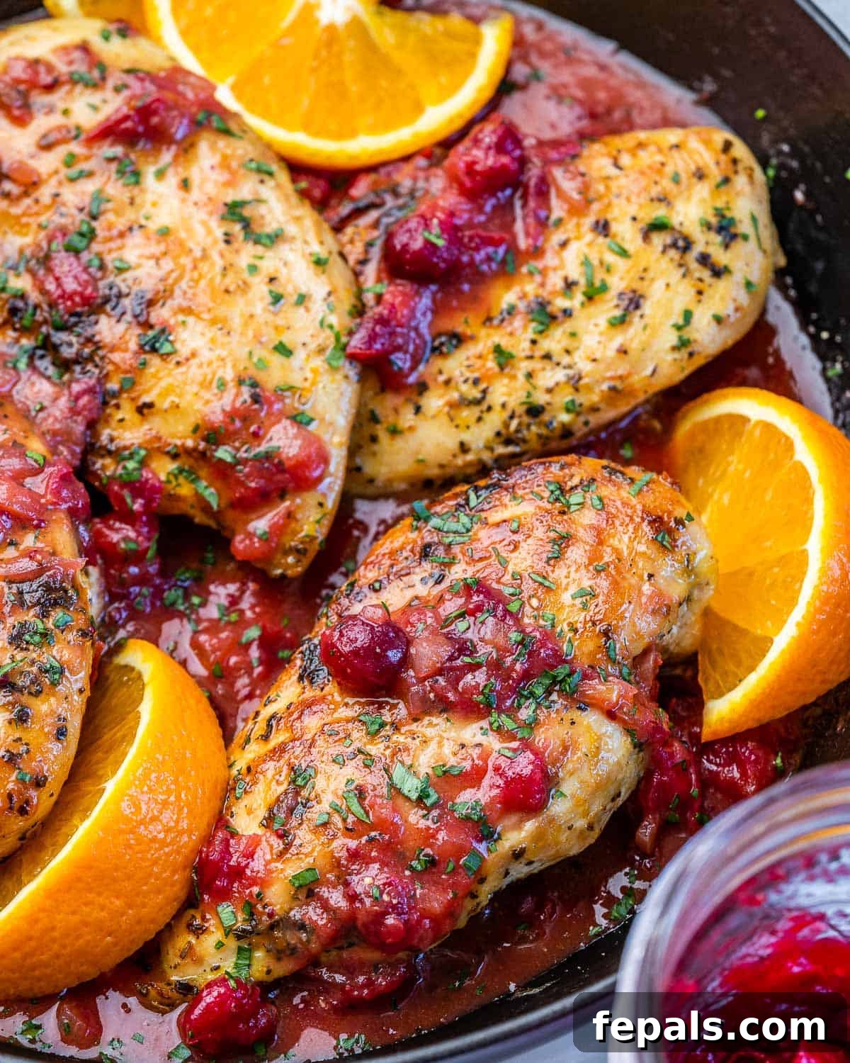 Zesty Cranberry Orange Chicken 6 Chicken breasts cooked in a pan with cranberry sauce and oranges.