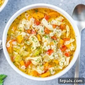 Delicious chicken pastina soup with small pasta, chicken, and vegetables in a round white bowl.