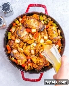 Chicken and broth added to vegetables in a skillet