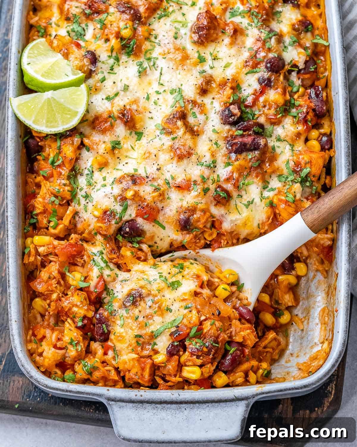 Classic Mexican chicken casserole in a white baking dish, ready to serve with a wooden spoon.