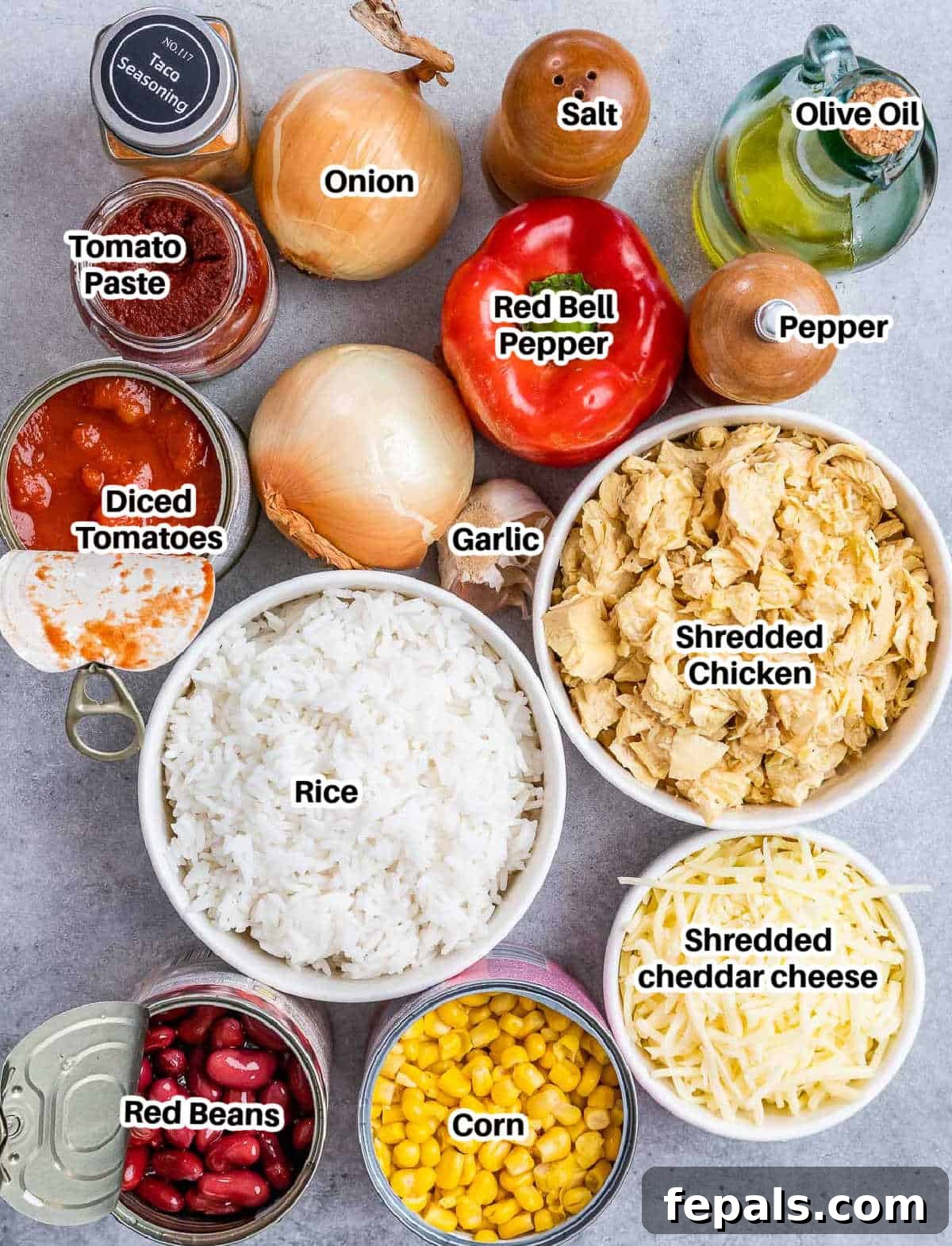 A vibrant selection of fresh ingredients including bell peppers, onions, garlic, canned tomatoes, corn, and shredded chicken, laid out for Mexican chicken casserole preparation.